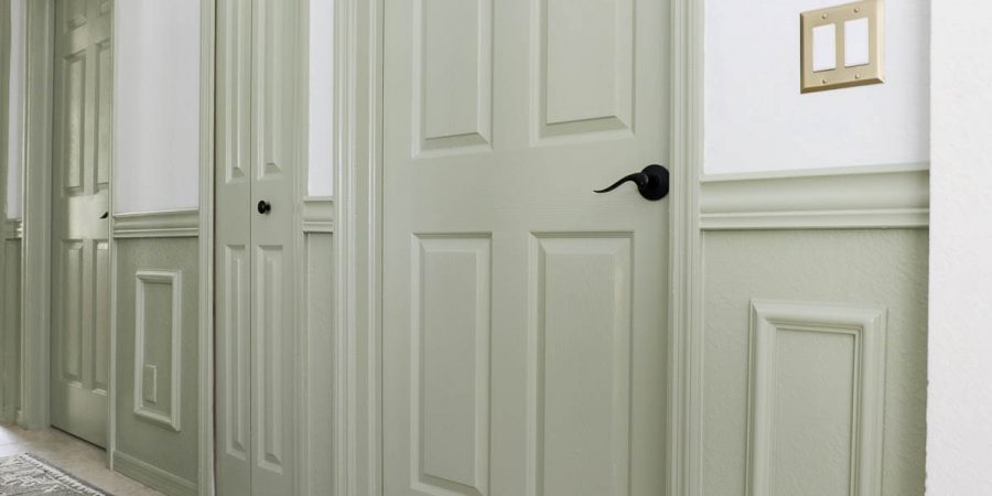 Sage green painted doors and wainscoting trim in a hallway